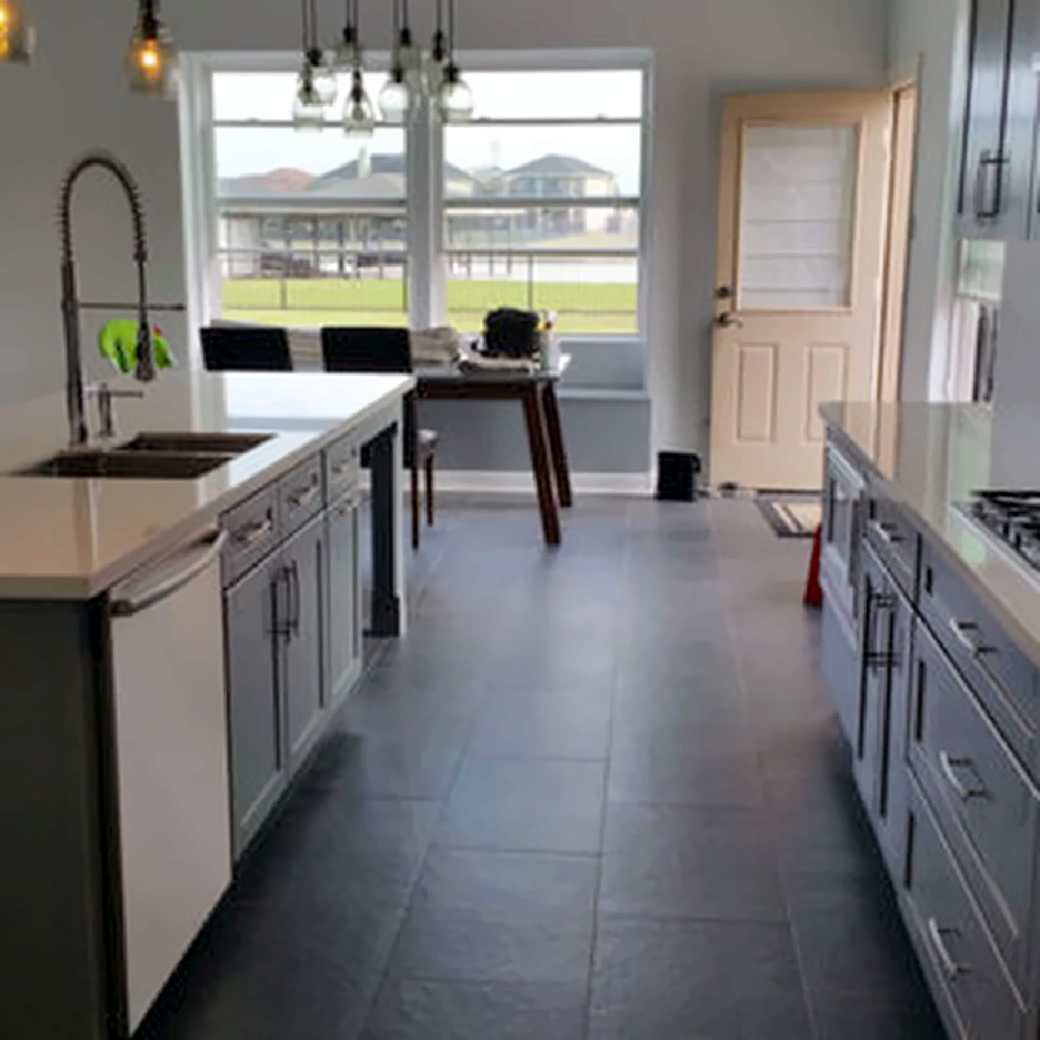 Gray shaker kitchen remodel with white perimeter counters, slate tile flooring, and a window over the dining table