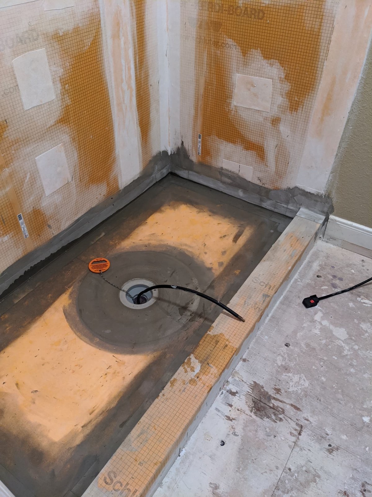 Shower under construction with Schluter waterproofing panels, sealed joints, and an integrated shower drain before tile installation